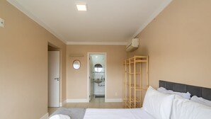 A hotel room with a bed, a wooden shelf unit, a bathroom visible through an open door, and a round mirror on the wall. - Apart w/ Pool 400m Praia dos Ingleses Posc0311 (Florianópolis)