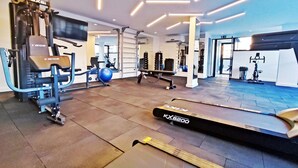 Un gimnasio con equipo de ejercicio, cinta de correr y un espejo grande.