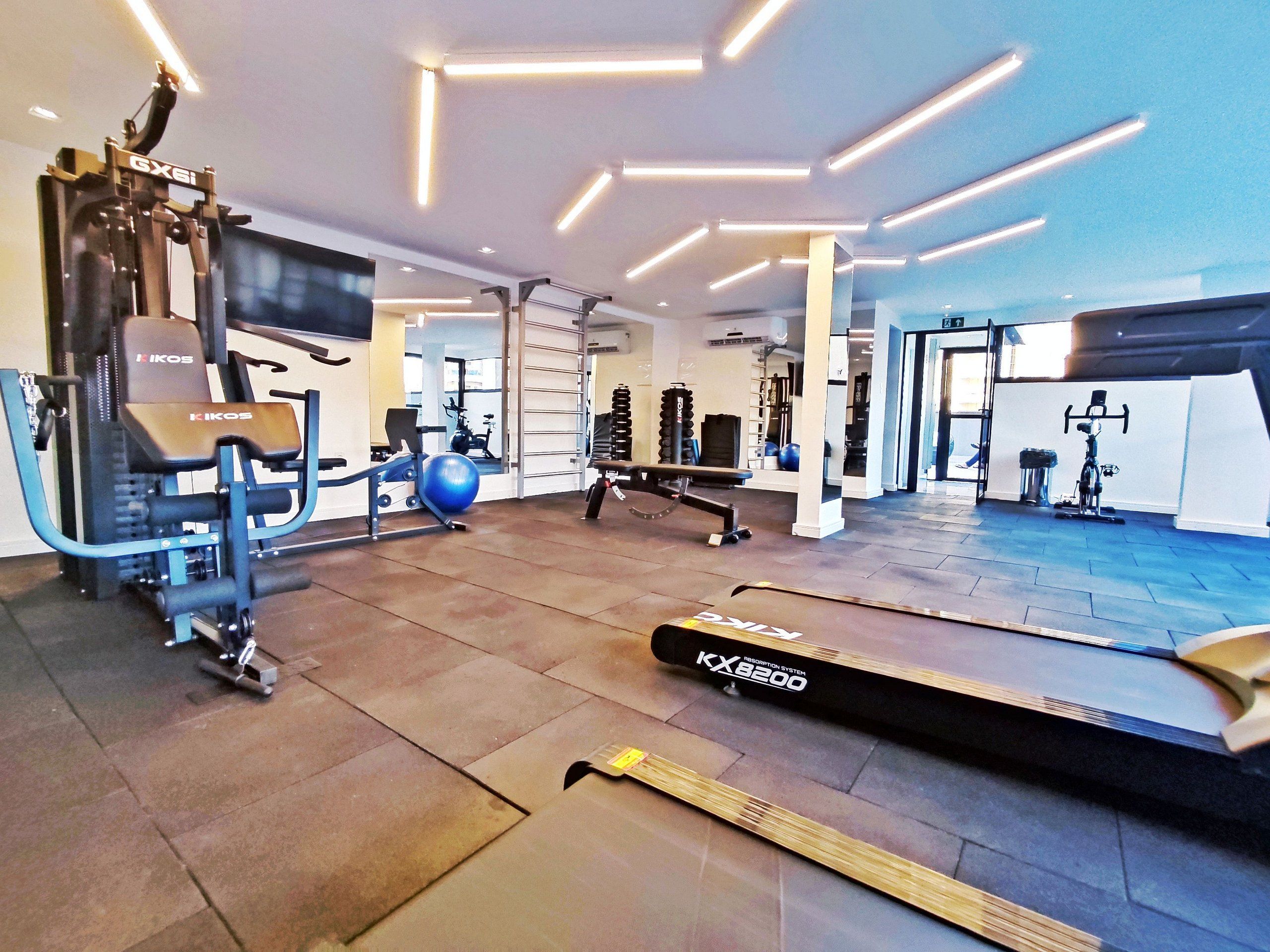Una palestra con attrezzature per esercizi, un tapis roulant e uno specchio a parete.