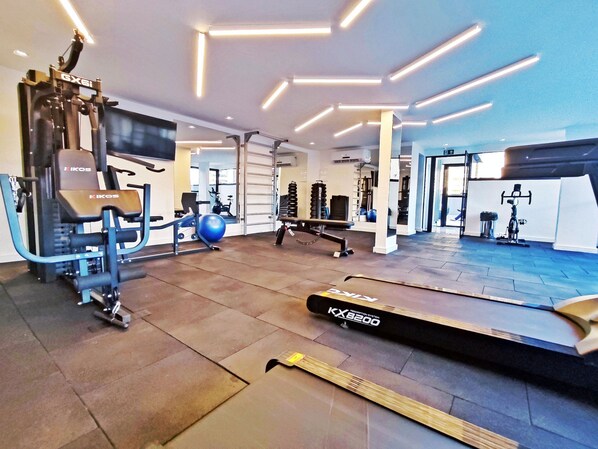 Un gimnasio con equipo de ejercicio, cinta de correr y un espejo grande.