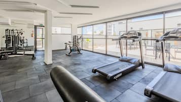 Un gimnasio con cintas de correr, bicicletas estáticas y máquinas de pesas.