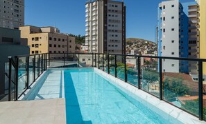 A rooftop pool with a glass balustrade, surrounded by high-rise buildings. - Beautiful Studio in Pocos de Caldas MG Pgo402 (Poços de Caldas)
