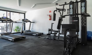 Een fitnessruimte met loopbanden, krachttoestellen en een muurbeugel voor optrekken.