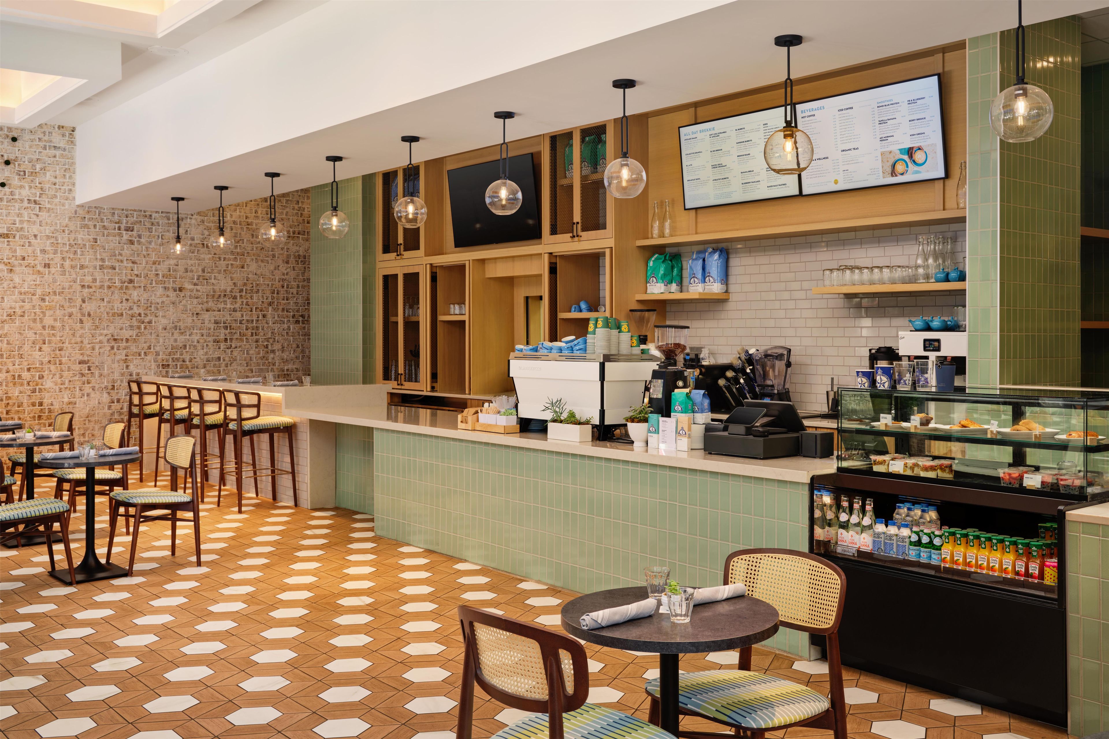Een café met een bakstenen muur, een houten toonbank en een vloer met een honingraatpatroon.