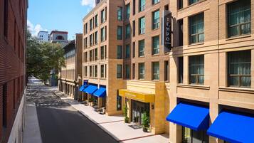 A hotel with a modern facade, multiple floors, and blue awnings over the entrance.