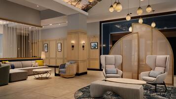 A modern lobby with a sectional sofa, armchairs, a round coffee table, and pendant lighting.