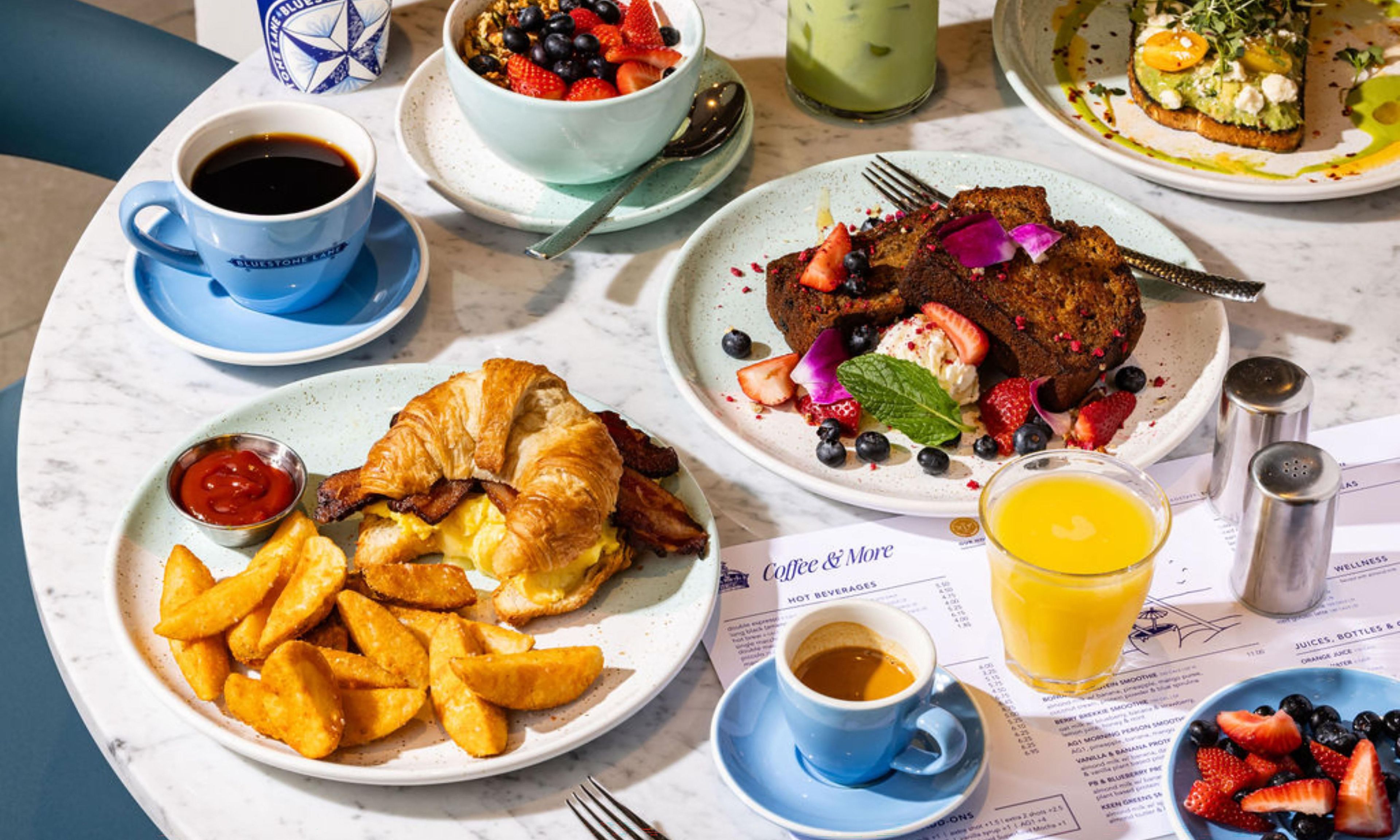 Una mesa de desayuno con platos de comida, una taza de café, un vaso de jugo y un menú.