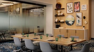 Een vergaderzaal met een lange tafel, stoelen, glazen wanden en kunstwerken aan de muren.