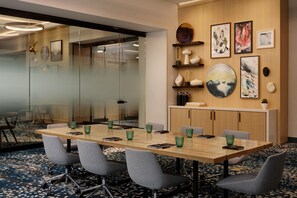 Une salle de conférence avec une longue table, des chaises, des murs en verre et des œuvres d’art accrochées aux murs.