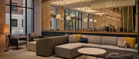 A modern living room with a sectional sofa, a round coffee table, and a wicker chair.