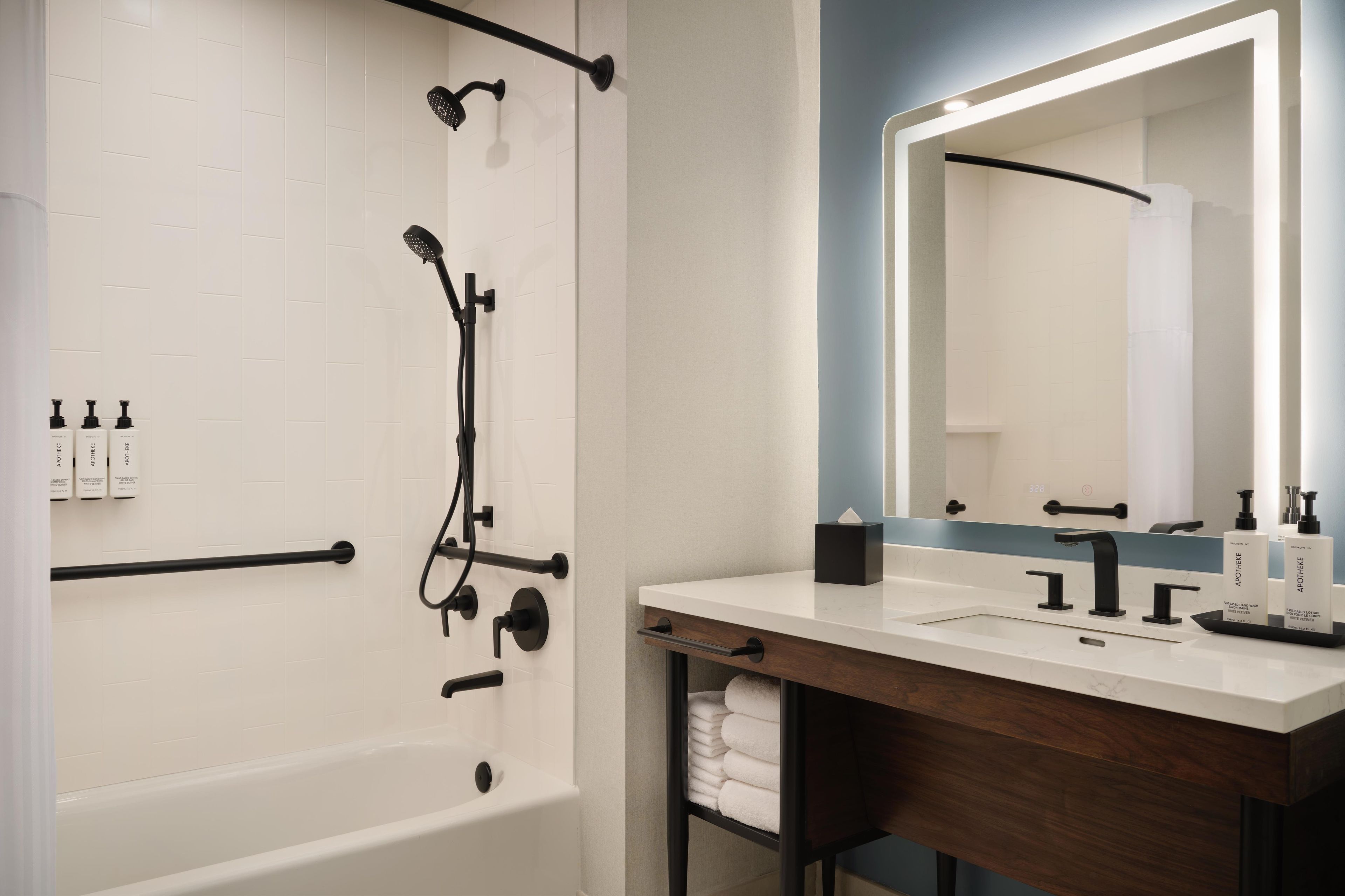 A modern bathroom with a bathtub, a shower, a vanity with a mirror, and toiletries.