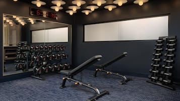 Een sportschool met gewichthefapparatuur, een digitale klok en een spiegel.