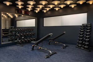 Ein Fitnessraum mit Gewichthebern, einer Digitaluhr und einem Spiegel.