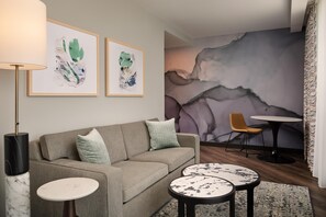Un salon moderne avec un canapé, deux tables rondes et des œuvres d’art abstraites accrochées au mur.