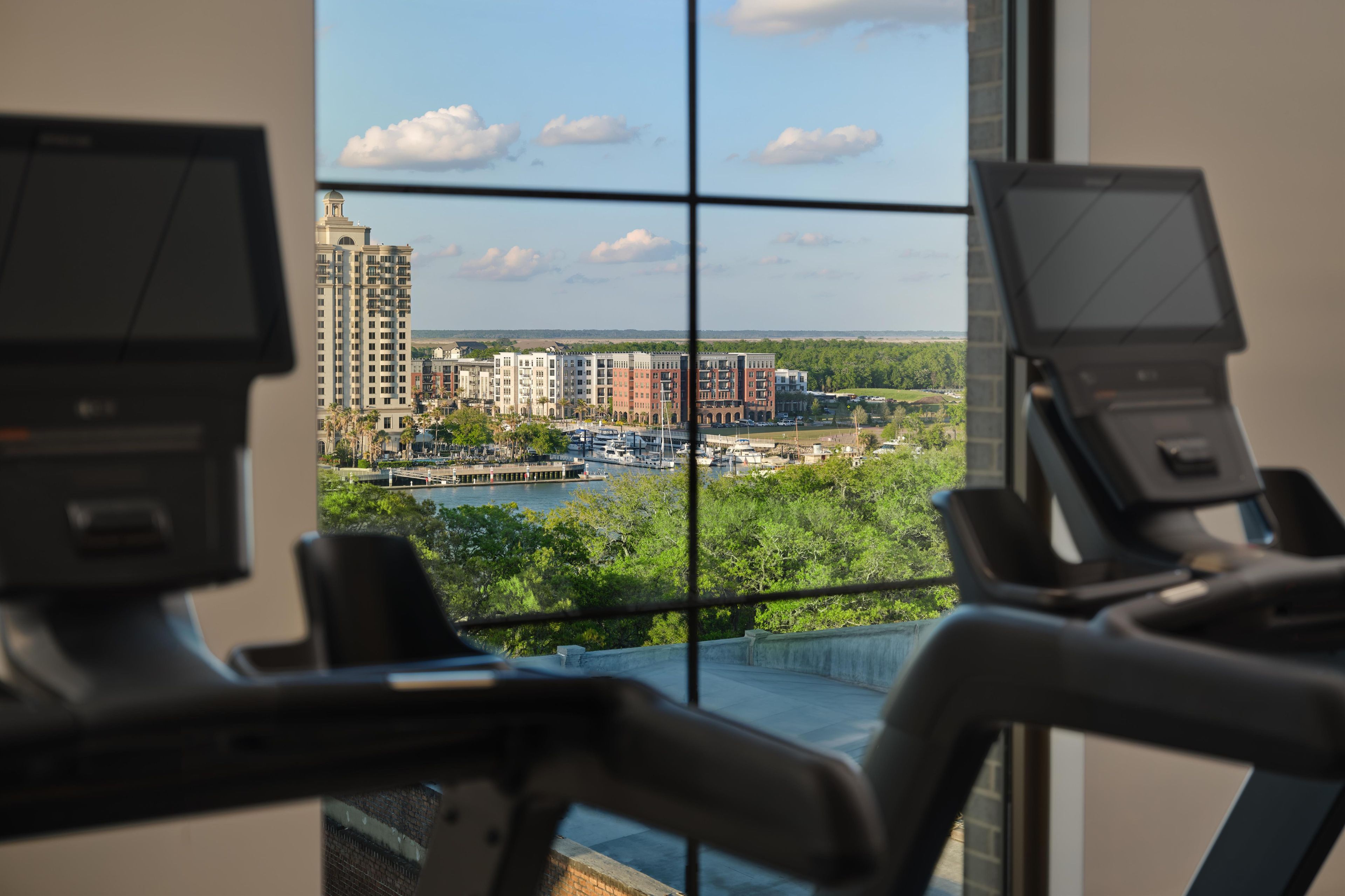 Ein Fitnessstudio mit Trainingsgeräten und Blick auf eine Stadtlandschaft durch große Fenster.