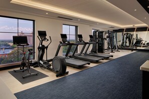 Un gimnasio con cintas de correr, elípticas y equipo de pesas.