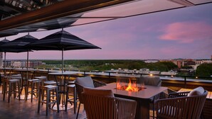 An outdoor seating area with tables and chairs, umbrellas, and a fire pit.
