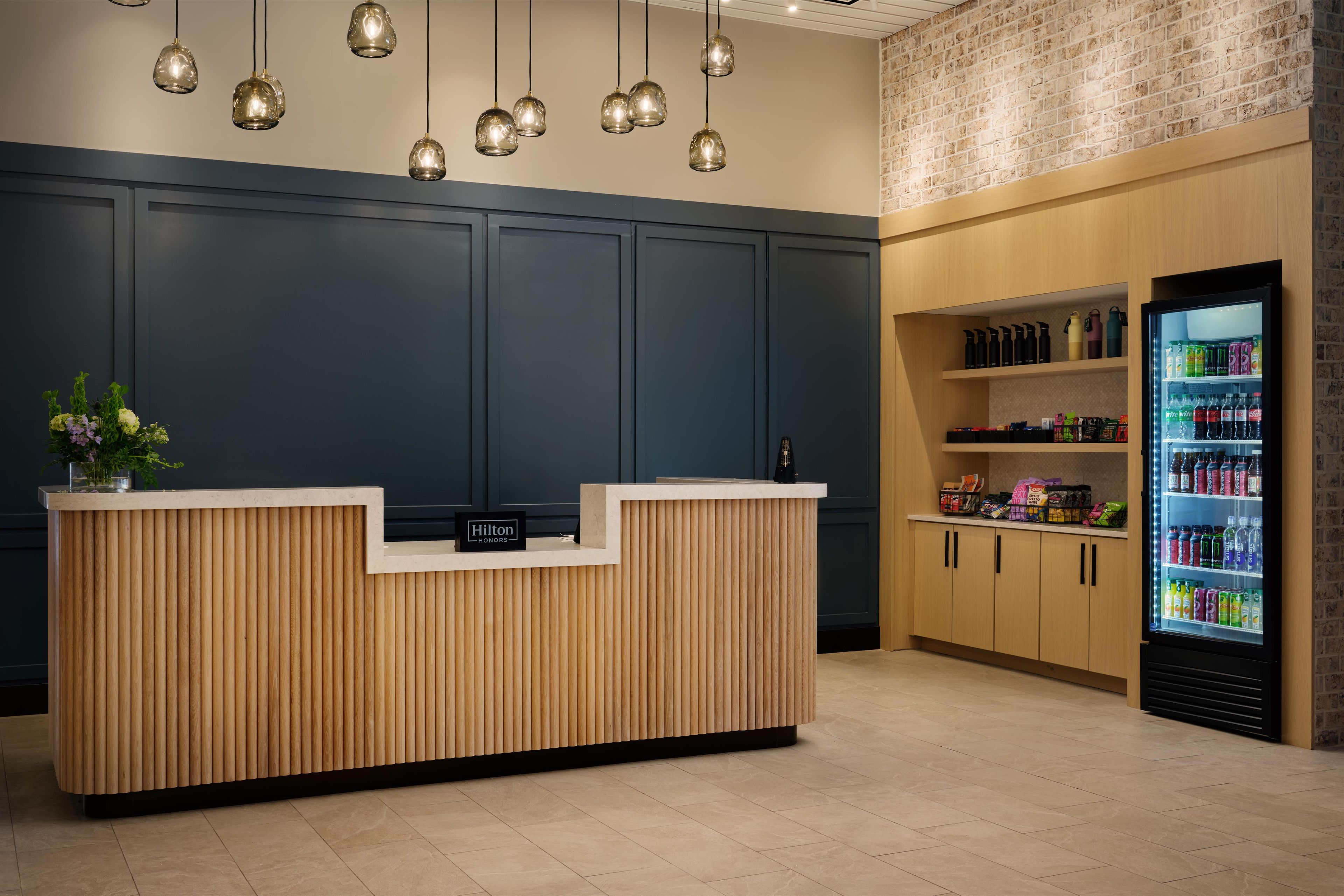 A hotel reception desk with a wooden finish, a minibar, and a beverage refrigerator.