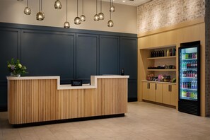 Un comptoir d’accueil en bois, un minibar et un réfrigérateur pour boissons.