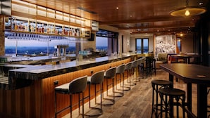 A bar area with a long counter, multiple stools, and a view of the cityscape.