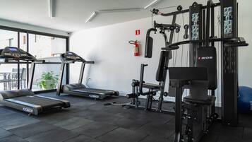 Un gimnasio con cintas de correr, máquinas de pesas y una barra de dominadas en la pared.