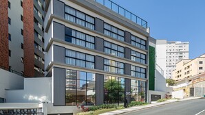 A modern hotel with multiple floors, large windows, and a green vertical garden. - Cozy Apartment Close to the Center Pgo309 (Poços de Caldas)