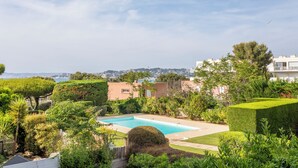Une piscine entourée d’une végétation luxuriante, offrant une vue sur le paysage urbain au loin.
