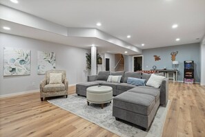 A modern living room with a sectional sofa, a patterned rug, and artwork on the walls. - Family-Friendly 4BR | King Beds + Game Room (Bellevue)