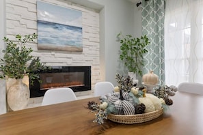 A dining area with a fireplace, white chairs, and a table with decorative items. - Family-Friendly 4BR | King Beds + Game Room (Bellevue)