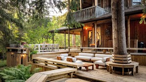 Una terraza de madera con asientos exteriores, rodeada de árboles.