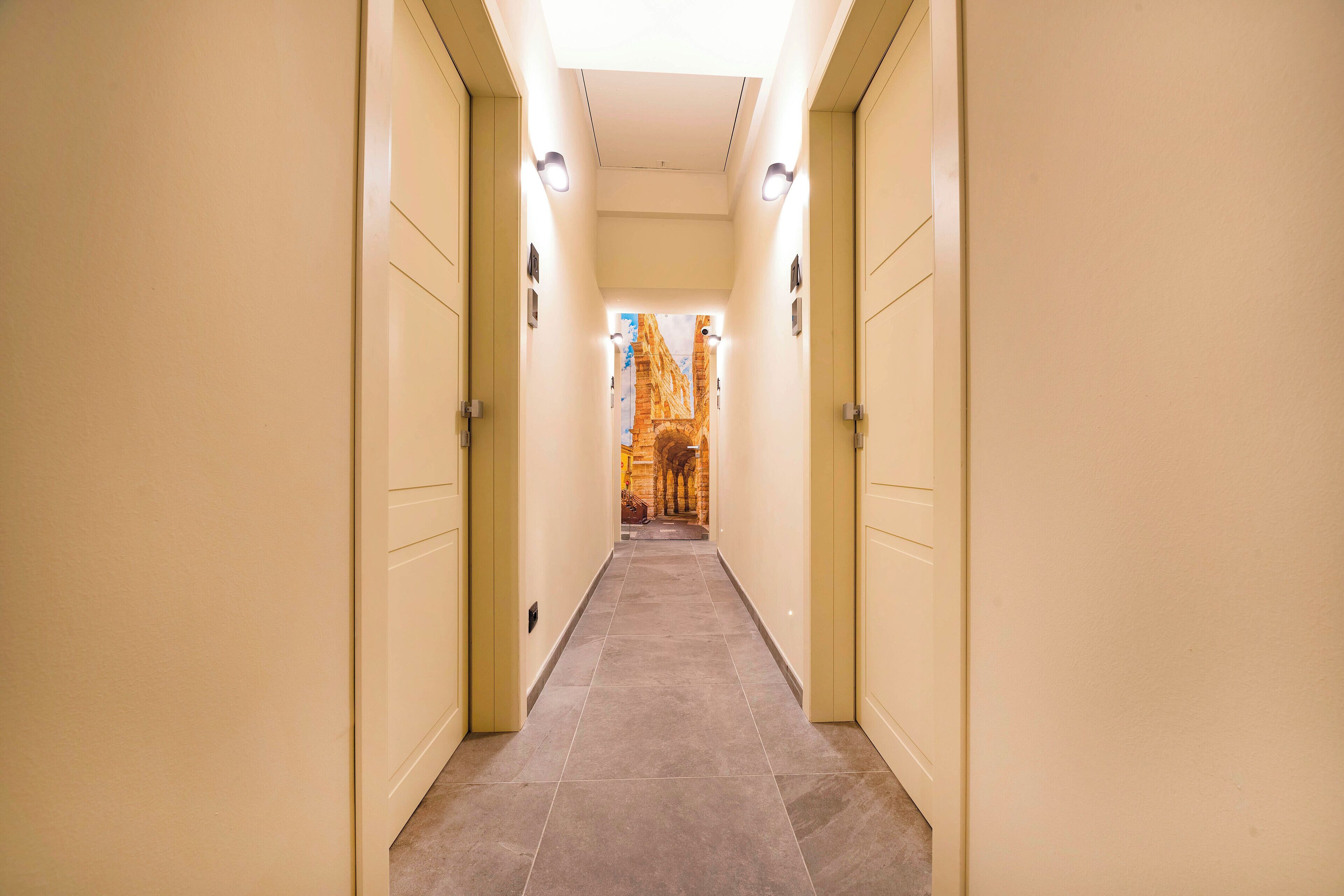 Un corridoio con pareti e porte beige che conduce a una stanza con vista su un edificio.