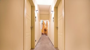 A hallway with beige walls and doors, leading to a room with a view of a building. - Italian flat - Verona's River (Verona)