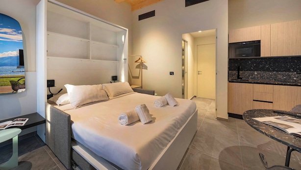 A modern hotel room with a large bed, a desk, and a kitchenette. - Italian flat - Verona's River (Verona)