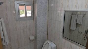 Un baño con inodoro, lavamanos y espejo.