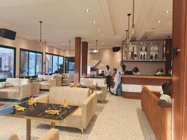 Un moderno vestíbulo de hotel con áreas de descanso, una recepción y un bar.