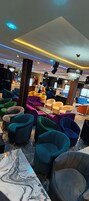 Un vestíbulo de hotel con sillones coloridos, una mesa de centro de mármol y una araña.