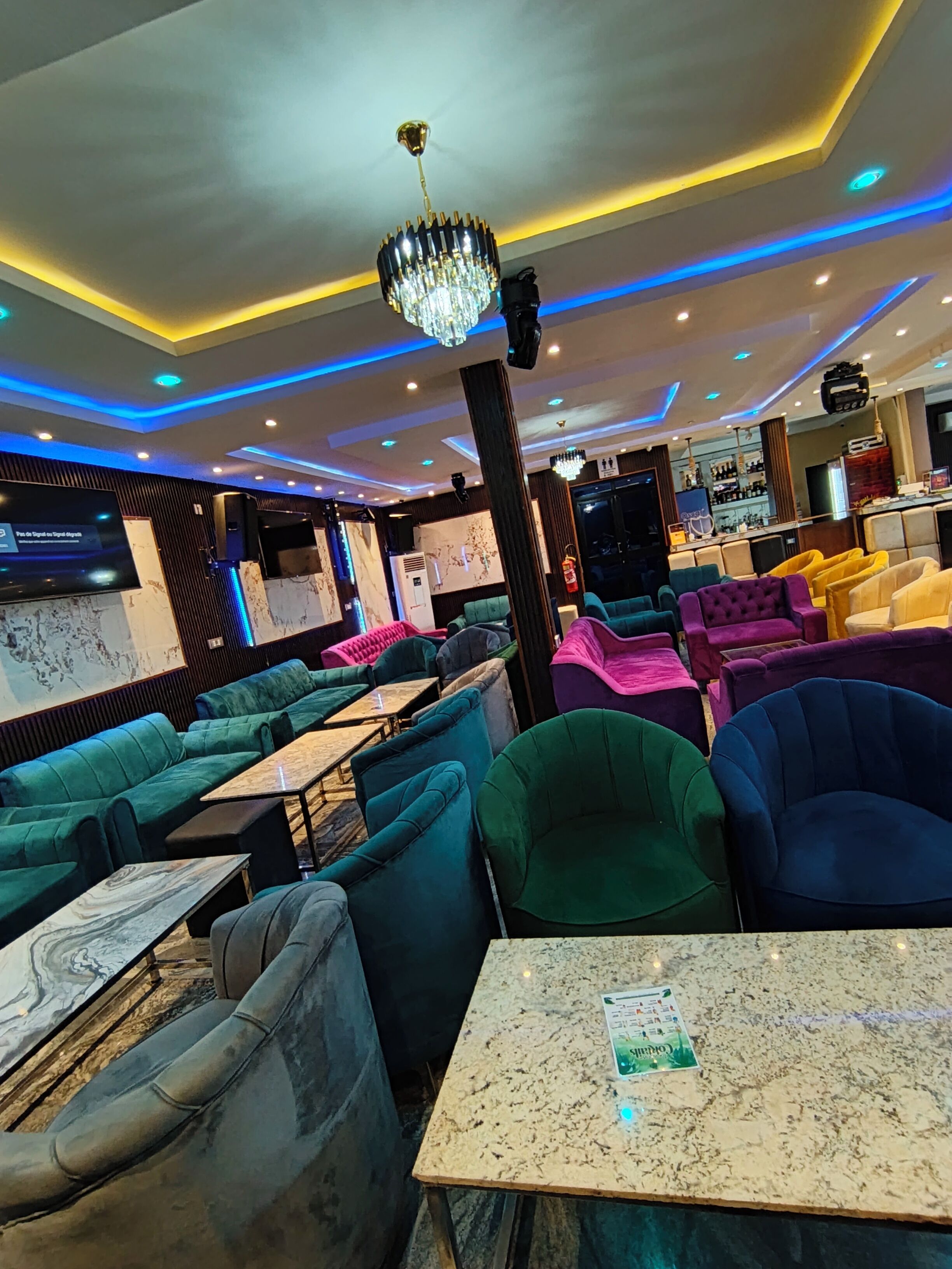 A modern lounge area with plush seating, a bar, and ambient lighting.