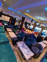 Un espacio lounge moderno con diversas opciones de asientos, incluyendo sofás y sillones, dispuestos alrededor de mesas de mármol.