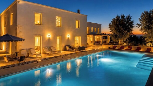 A modern building with a swimming pool, outdoor seating, and warm lighting.