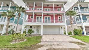 A multi-story residential building with balconies, a garage, and a paved driveway.
