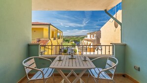 Een balkon met een tafel en stoelen, uitzicht op gebouwen en een heldere lucht.