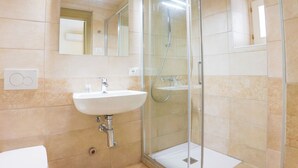 Ein Badezimmer mit Duschkabine, Waschbecken und Spiegel.