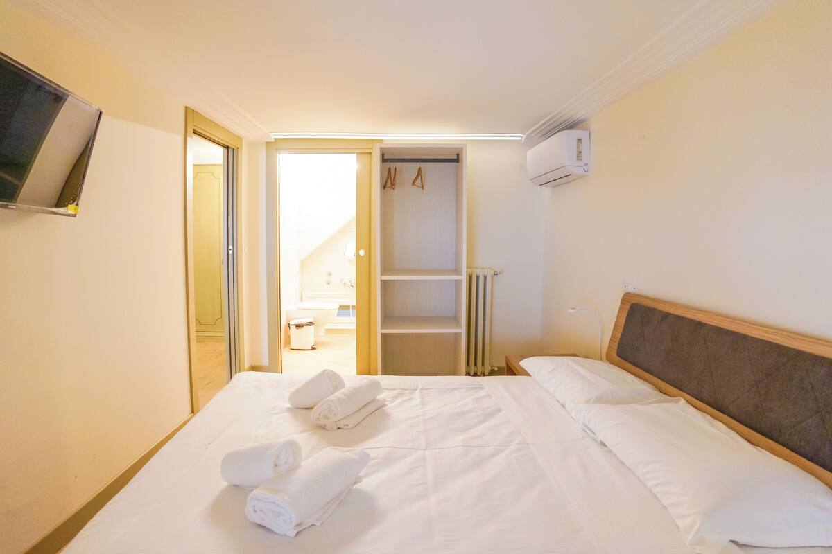 A hotel room with a bed, a wardrobe, and a television mounted on the wall.