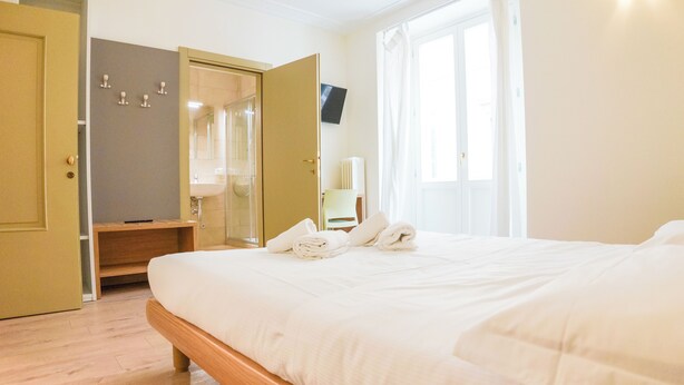 Ein Hotelzimmer mit einem Bett, einem Kleiderschrank, einem Spiegel und einem Fenster.