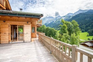 Une cabane en bois dotée d’un balcon donnant sur un paysage montagneux.