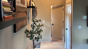 A modern hallway with a hanging light fixture, a bookshelf, a potted plant, and a bench.