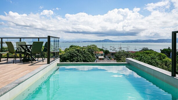 Une piscine sur le toit offrant une vue sur la mer et les montagnes.