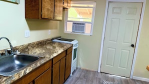 A kitchen with wooden cabinets, a granite countertop, a sink, and a stove.