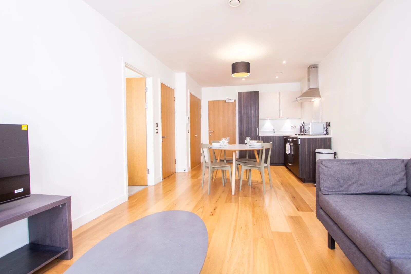 A modern apartment with a dining area, kitchen, and living room.