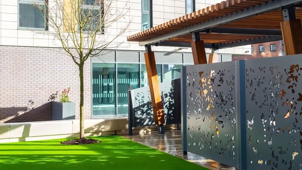 A modern building with a brick facade, large windows, and a green lawn. - The Slate Yard (Salford)